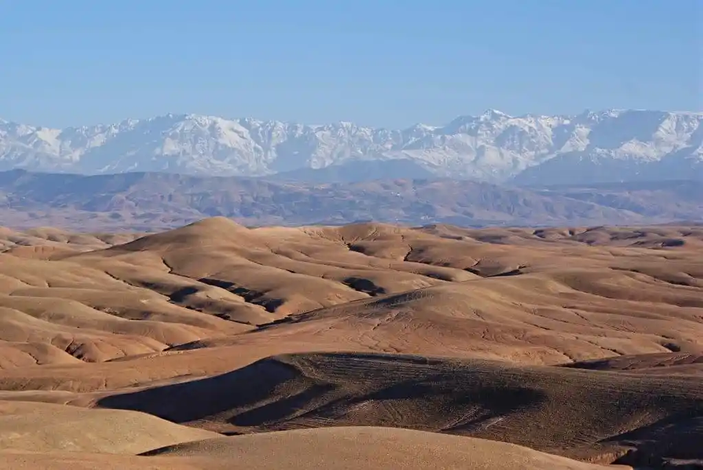 Vista panorámica del desierto de Agafay con terreno rocoso y las montañas del Atlas al fondo