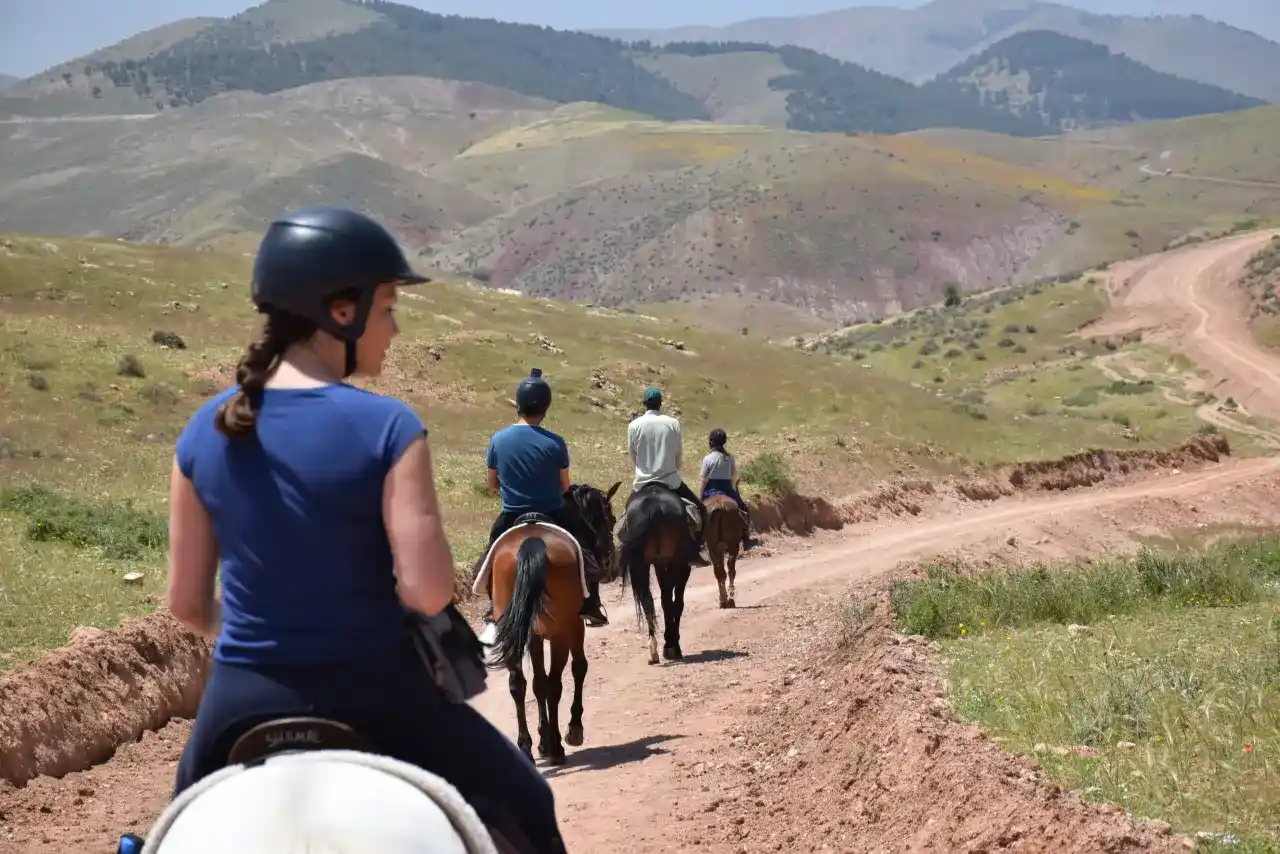 Horse riding through Atlas Mountain foothills with Berber village in background