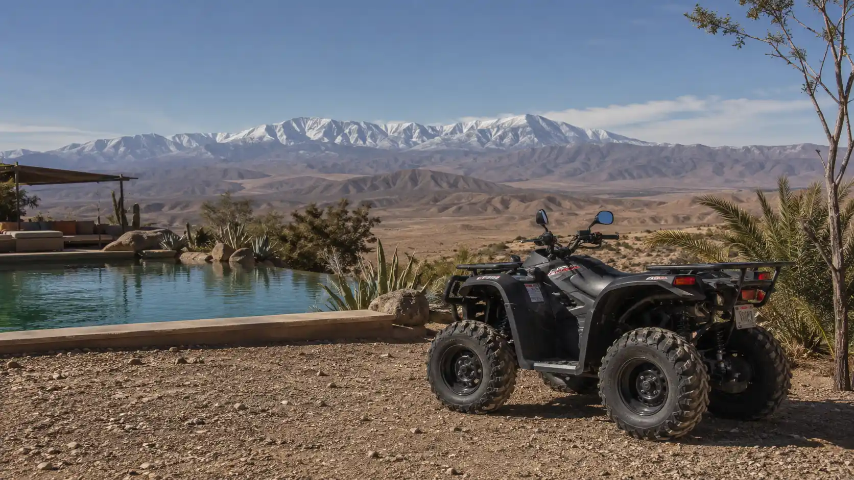 Quad bike parked next to a desert pool with Atlas Mountain views